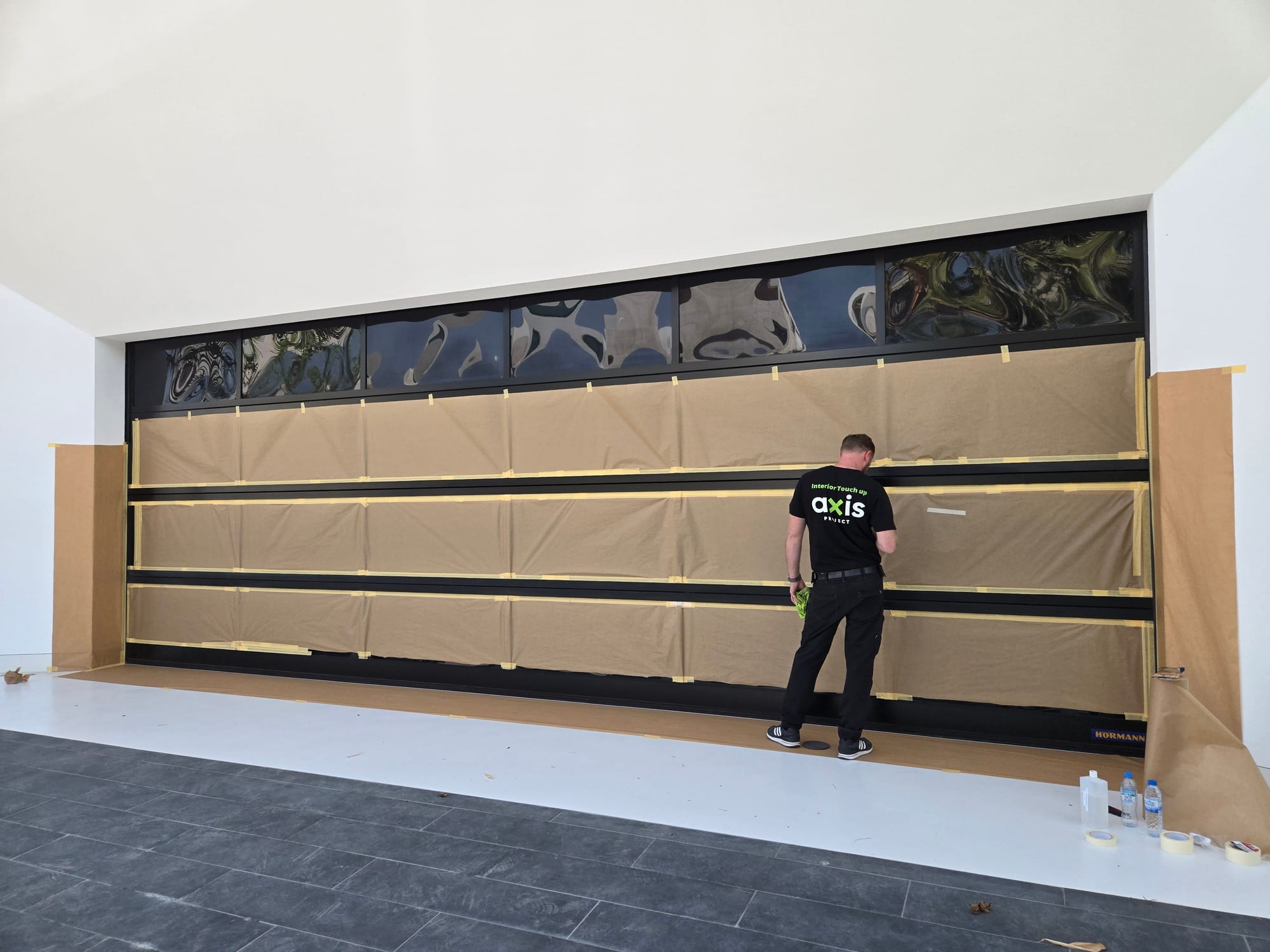 Large black aluminium glazed door masked for on-site refinishing